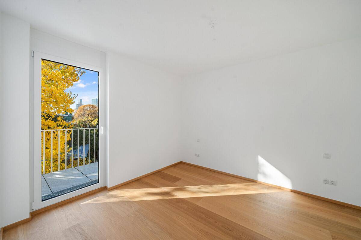 Lichtdurchfluteter Raum mit Holzboden und direktem Zugang zu einem französischen Balkon.