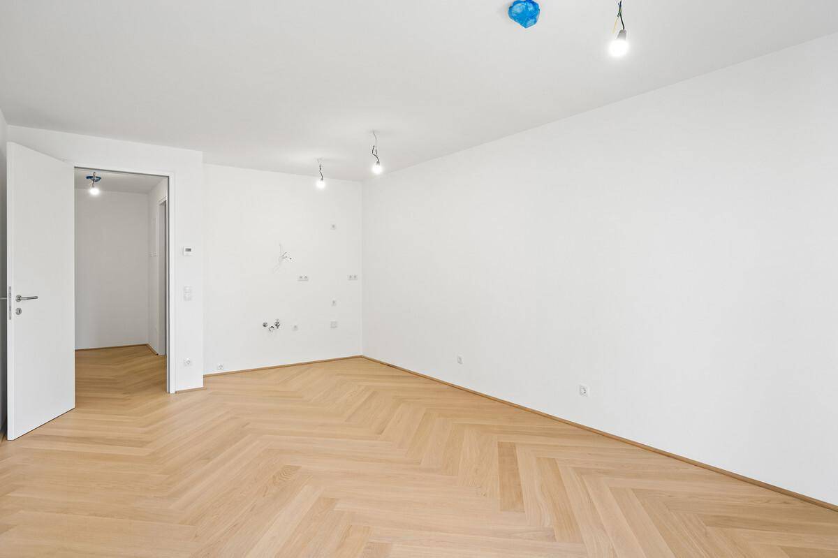 Geräumiges, helles Zimmer mit Fischgrätparkett und weißen Wänden, bereit zur individuellen Gestaltung.