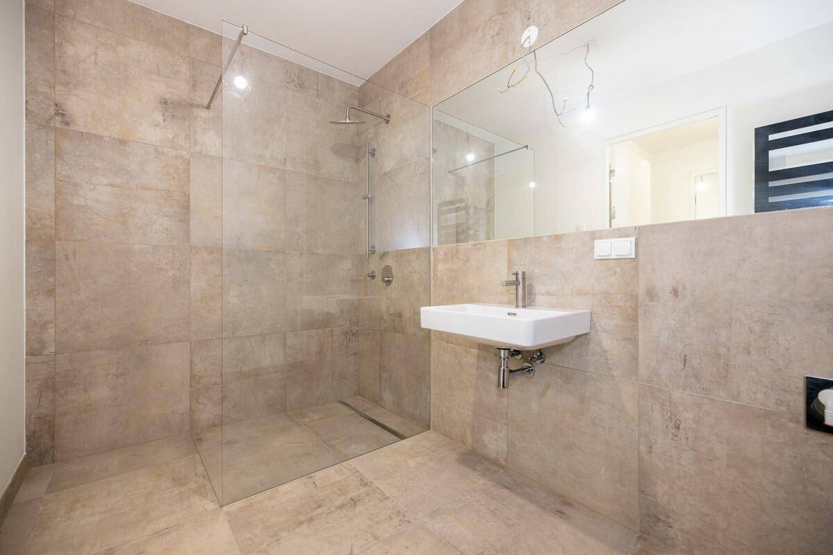 Modernes Badezimmer mit beigefarbenen Fliesen, ebenerdiger Dusche und Einzelwaschbecken.