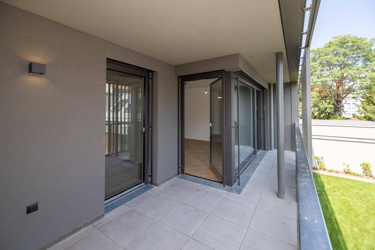 Heller Balkon mit Fliesenboden und Zugang zum Innenraum, ideal für entspannte Stunden im Freien.