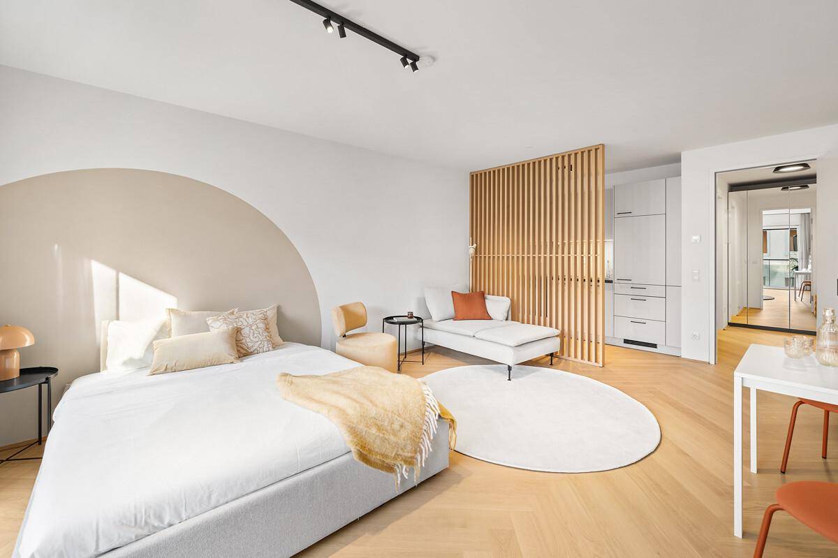 Stilvolles Schlafzimmer mit Holzboden, bequemer Chaiselongue und integriertem Stauraum.
