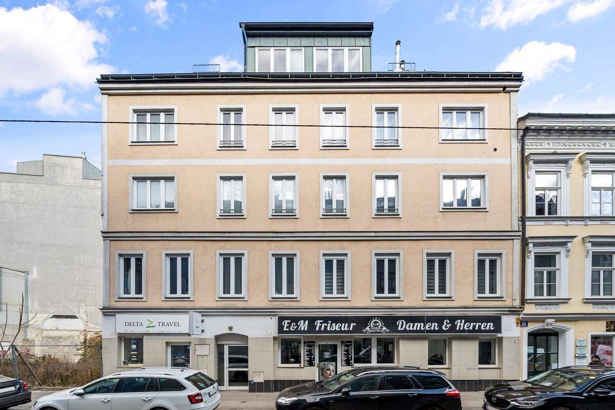 Klassische Fassade eines Mehrfamilienhauses mit Geschäften im Erdgeschoss.