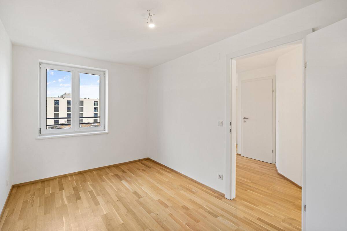 Geräumiges Schlafzimmer mit Parkettboden und großem Fenster mit Stadtblick.