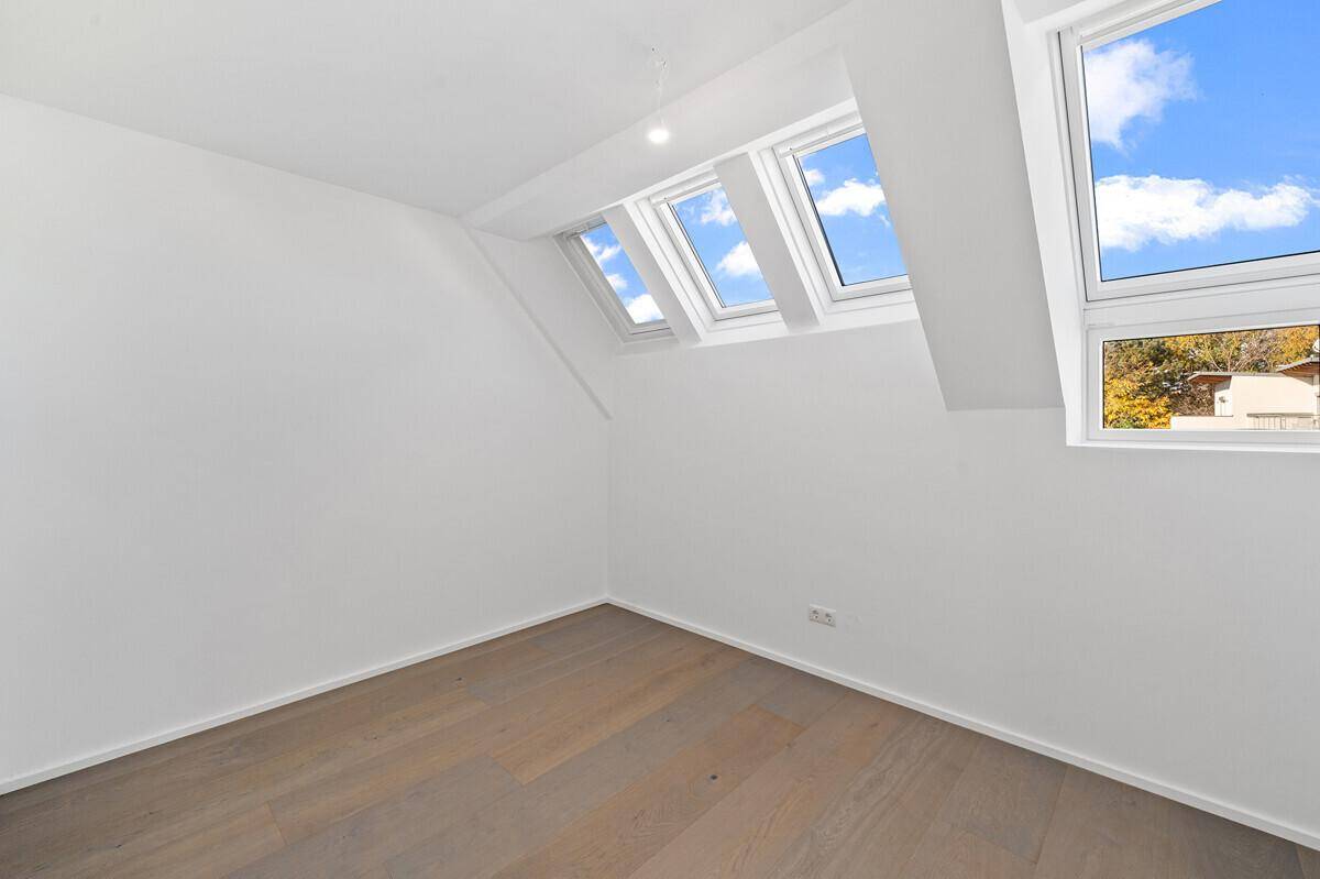 Heller Dachraum mit Holzboden und mehreren Dachfenstern, bietet viel natürliches Licht und eine schräge Decke.