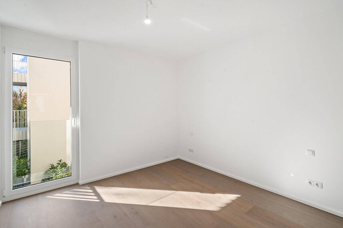 Helles Zimmer mit Holzboden und Balkonzugang, ideal als Schlaf- oder Arbeitszimmer.