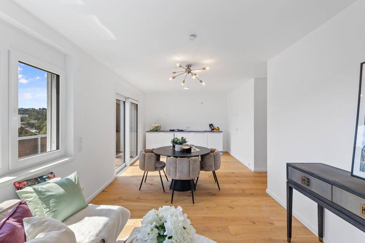 Heller Wohnraum mit Blick auf die moderne Küchenzeile und den Zugang zum Balkon.
