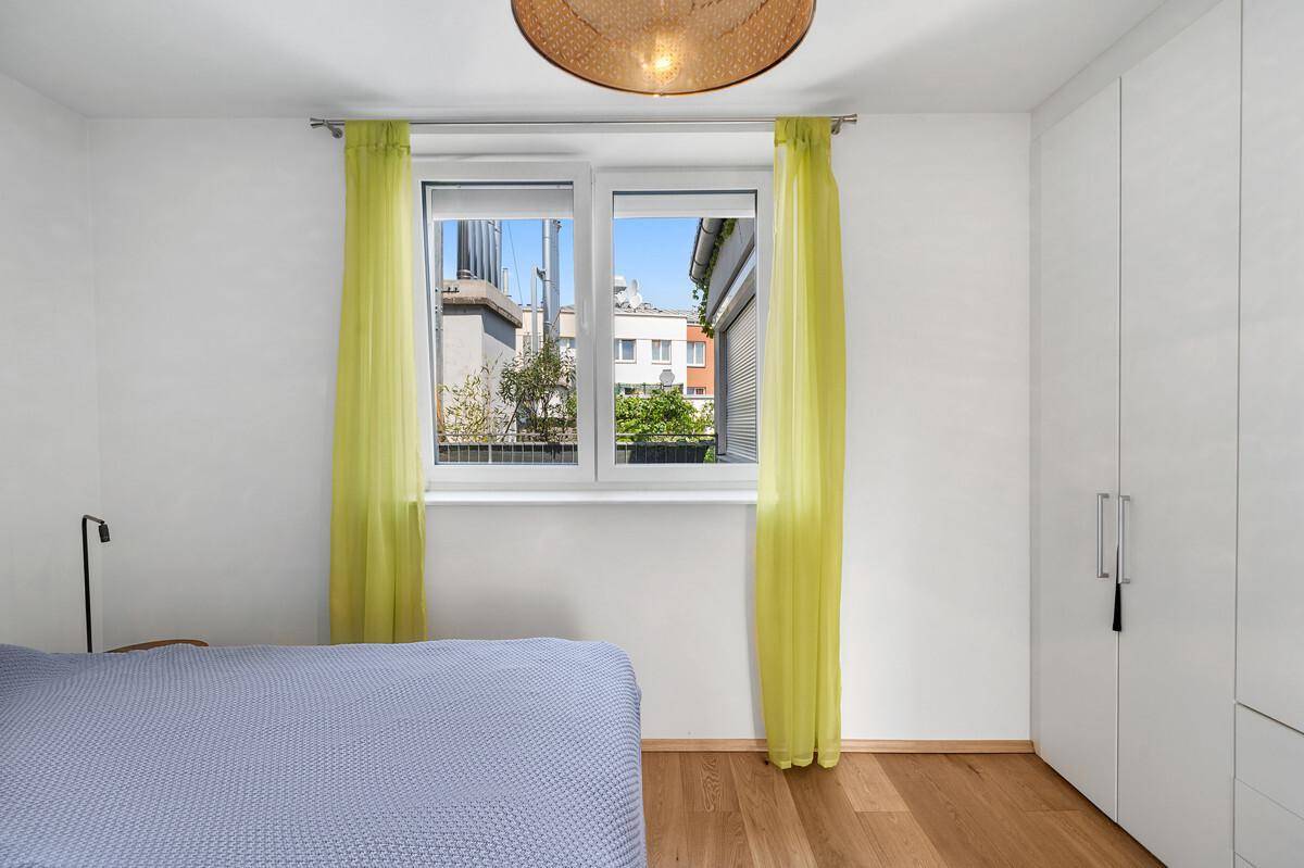 Schlafzimmer mit Doppelbett, weißen Einbauschränken und Fenster.