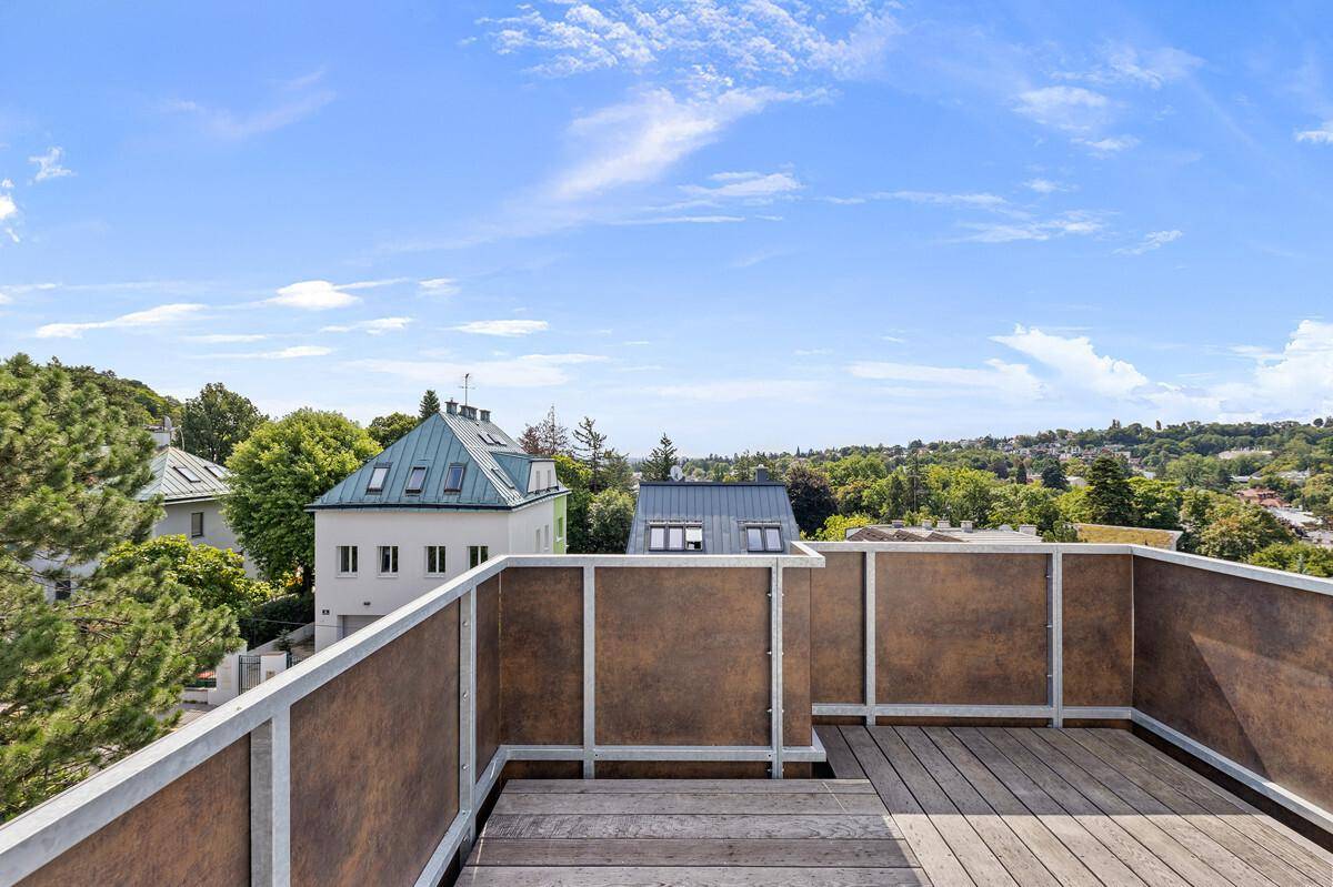 Balkon mit Holzboden und Blick auf die umliegenden Häuser und Bäume.