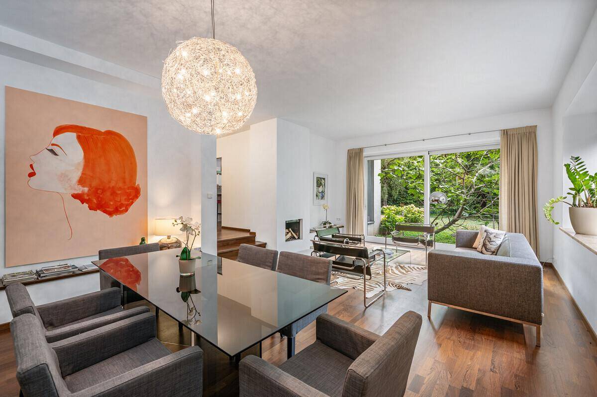 Stilvoller Wohn- und Essbereich mit modernem Esstisch, Kunstwerken und Zugang zum Garten.