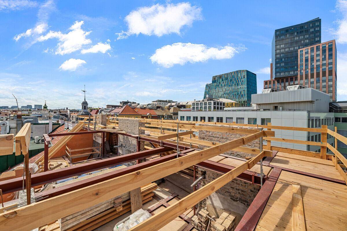 Dachbaustelle mit Holzrahmen und Blick auf moderne Hochhäuser und die Stadt.