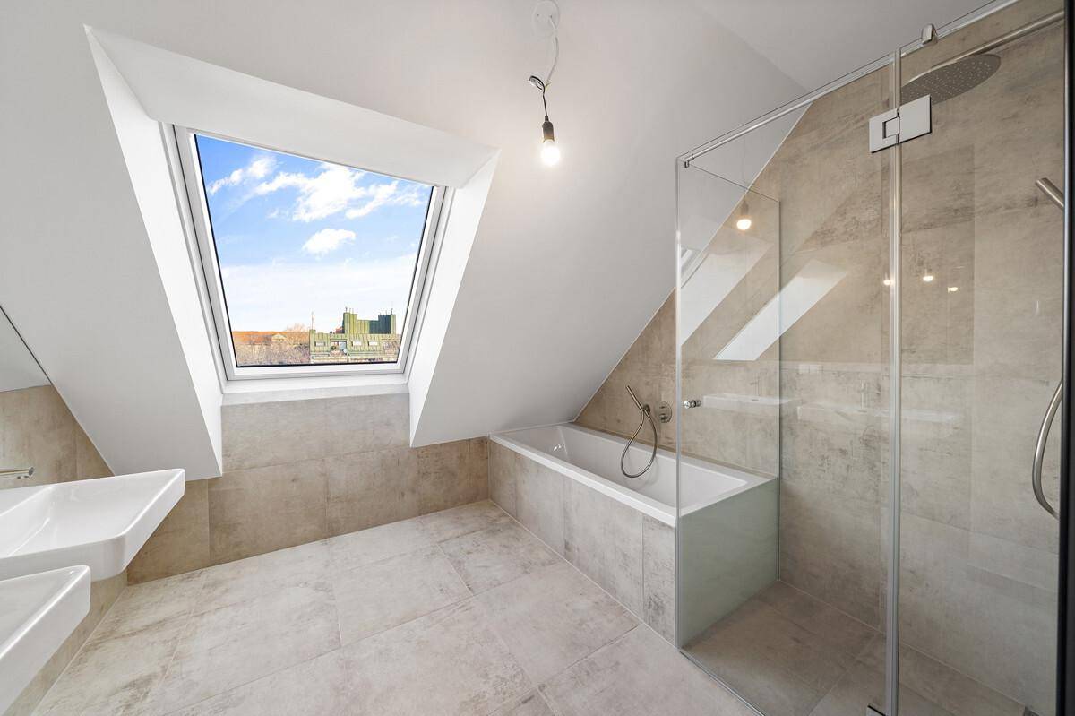 Modernes Badezimmer im Dachgeschoss mit Badewanne, Dusche, Doppelwaschbecken und Dachfenster.
