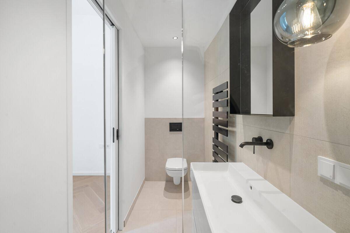 Stilvolles Badezimmer mit begehbarer Dusche, wandhängendem WC und modernem Waschtisch.