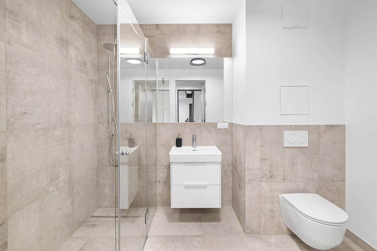 Modernes Badezimmer mit begehbarer Dusche, Wand-WC und eleganten beigefarbenen Fliesen.