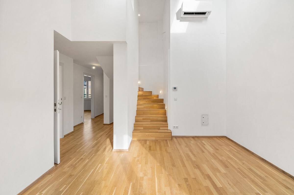 Lichtdurchfluteter Wohnbereich mit offener Holztreppe und minimalistischer Gestaltung.