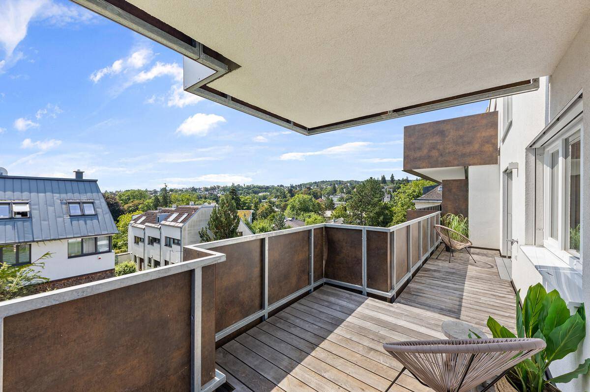 Geräumiger Balkon mit Holzboden und weitem Blick über die grüne Umgebung.
