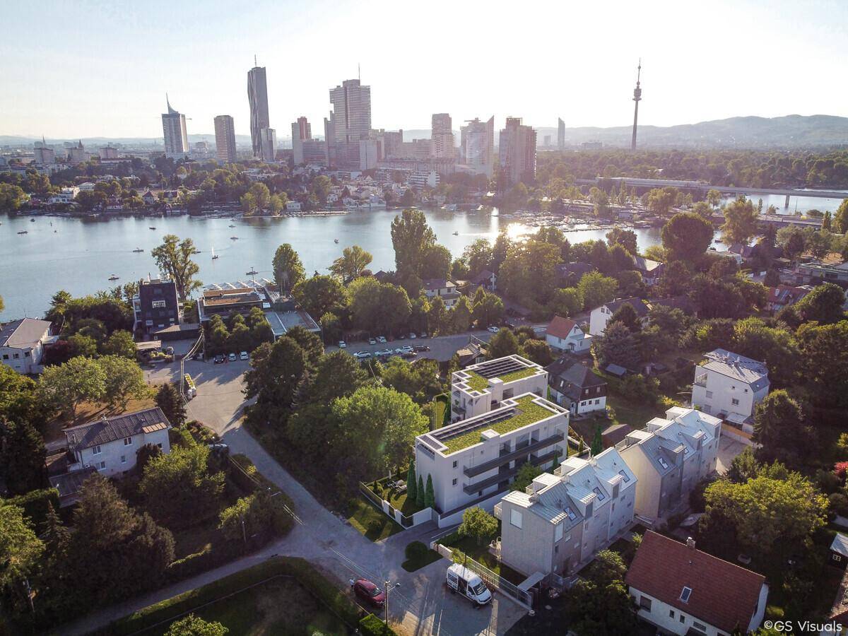 Luftaufnahme einer modernen Wohnsiedlung mit Gründächern, Stadt- und Seeblick.