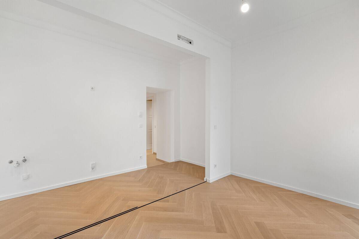 Leerer Raum mit Fischgrätparkett und Zugang zu einem weiteren Bereich, ideal für offenes Wohnen.