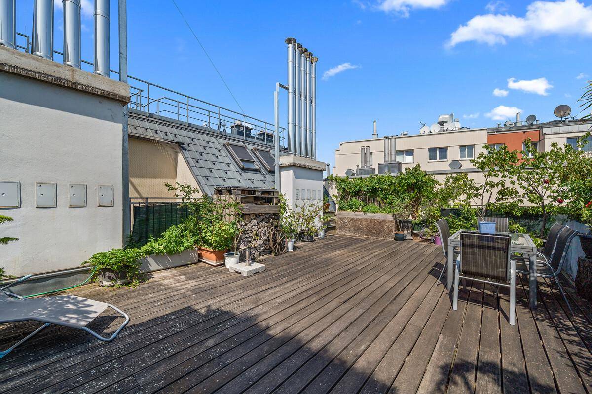 Sonniger Außenbereich auf der Dachterrasse mit Holzboden und Stadtblick.