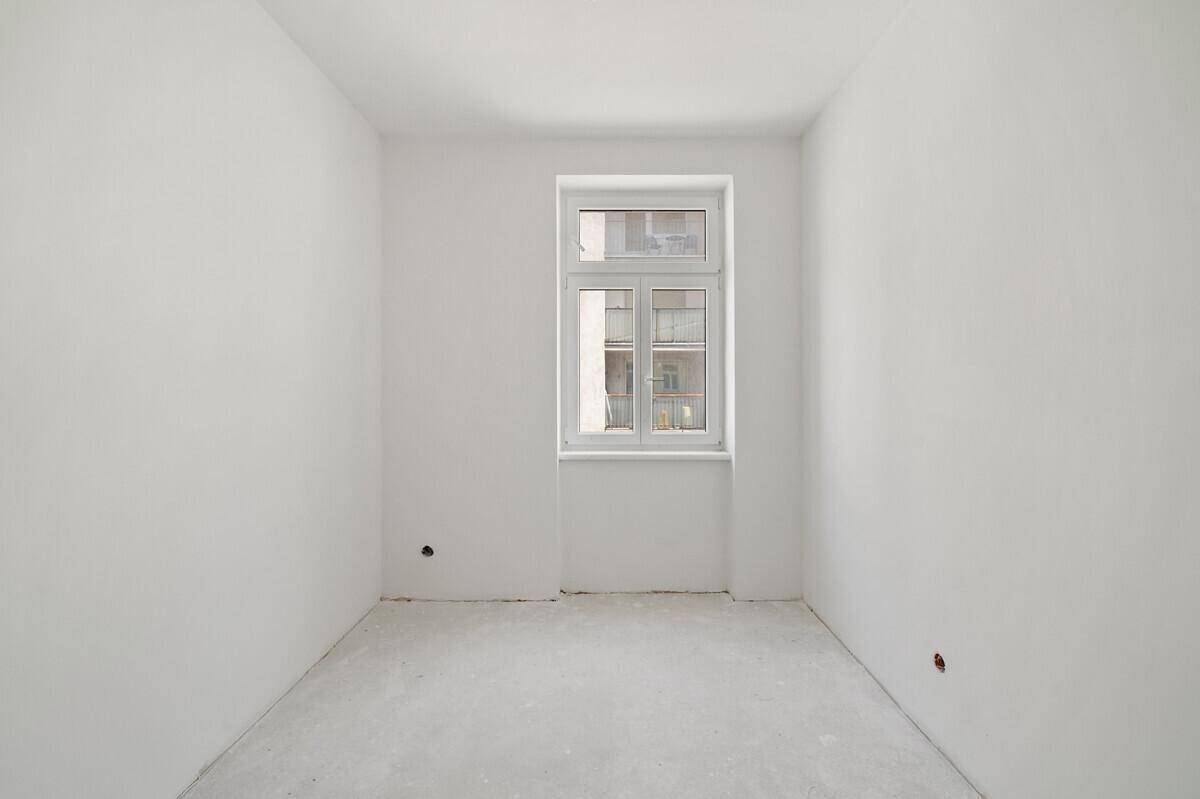 Helles Zimmer im Rohzustand mit einem Fenster, ideal für Schlaf- oder Arbeitszimmer.