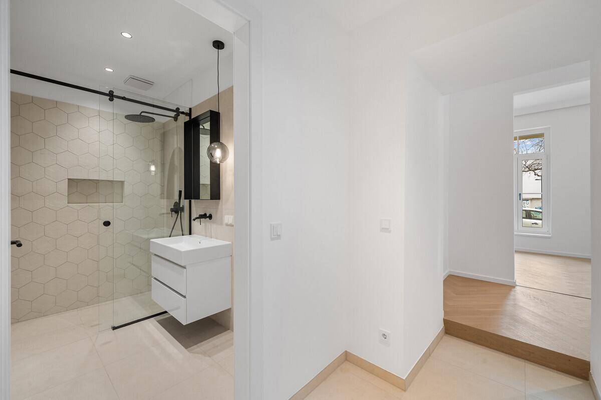 Heller Flur mit Zugang zu einem modernen Badezimmer und einem weiteren Wohnbereich.