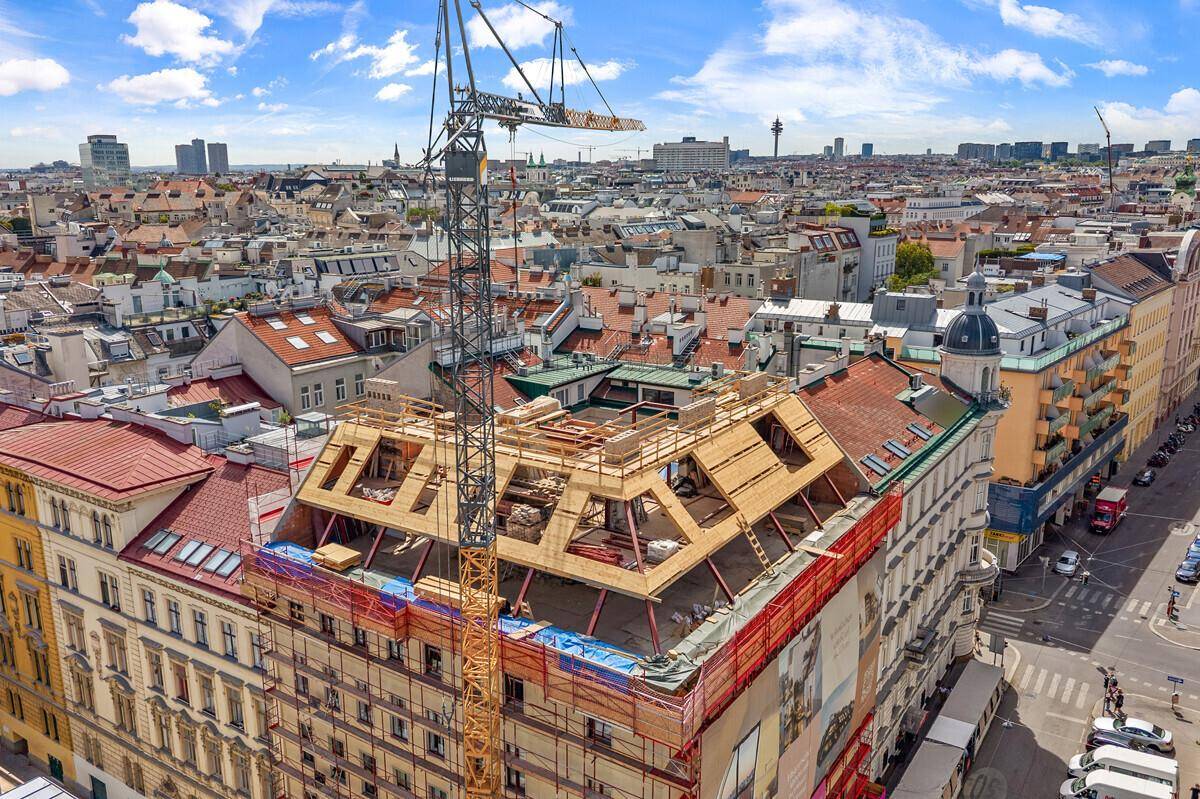 Luftaufnahme eines Gebäudes im Bau mit Dachausbau und Stadtpanorama.