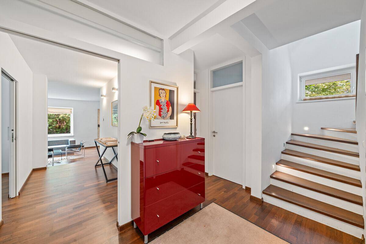 Heller Flur mit Holzboden, moderner Kommode und Treppe zum Obergeschoss, offen zum Wohnbereich.
