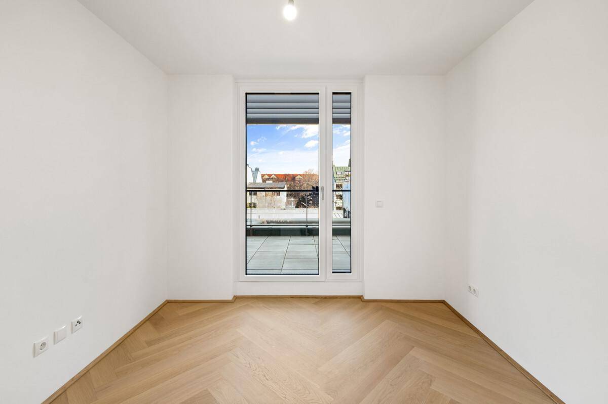Ruhiges Zimmer mit Parkettboden und Fenster mit Rollladen zur Außenterrasse.