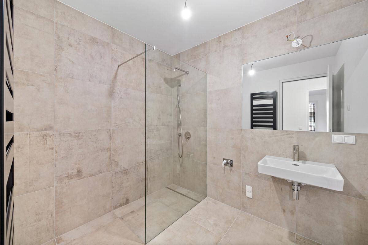Modernes Badezimmer mit großformatigen Fliesen, ebenerdiger Dusche und Einzelwaschbecken.