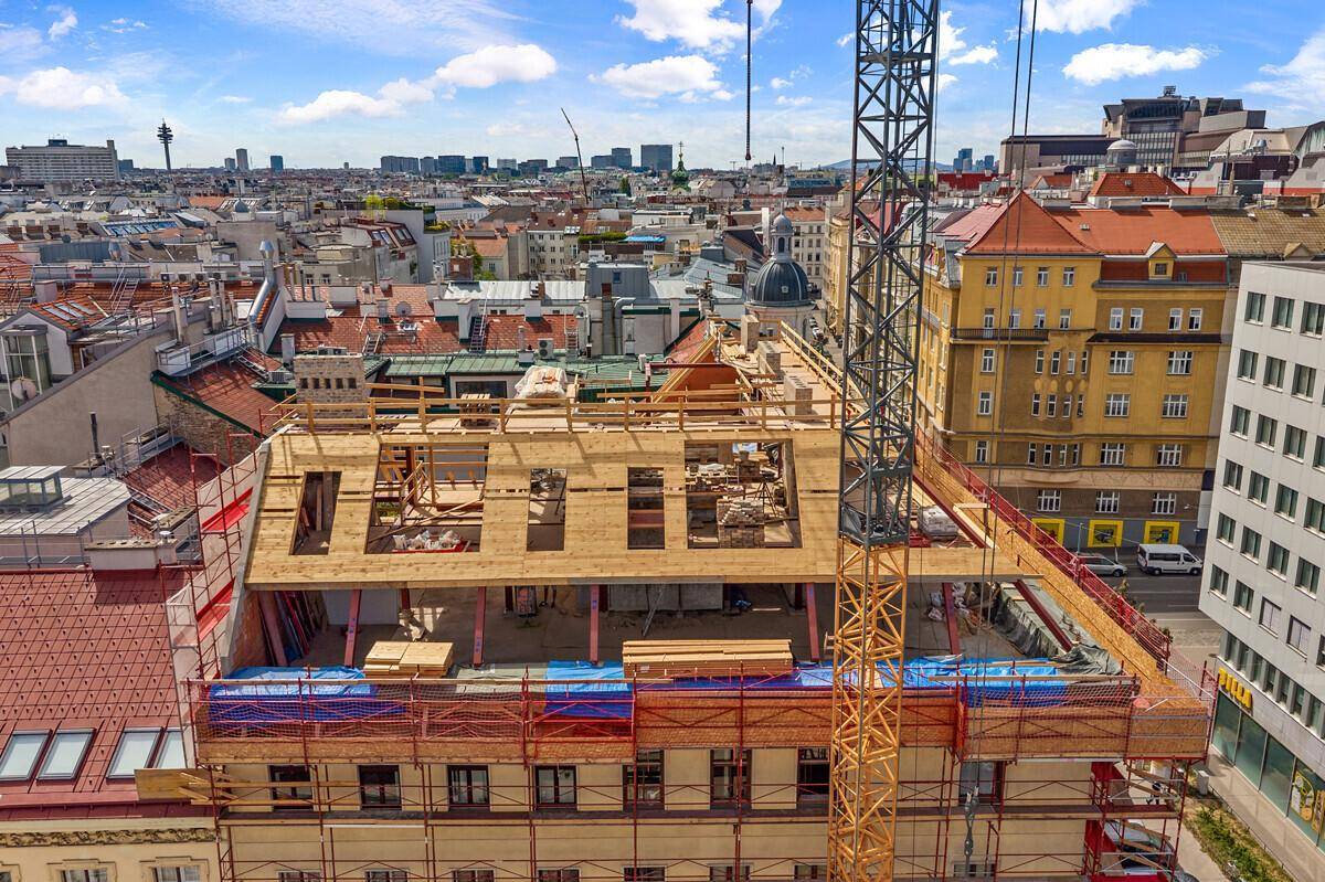 Dachausbau im Bau mit Holzbalken und Blick auf die umliegende Stadtlandschaft.