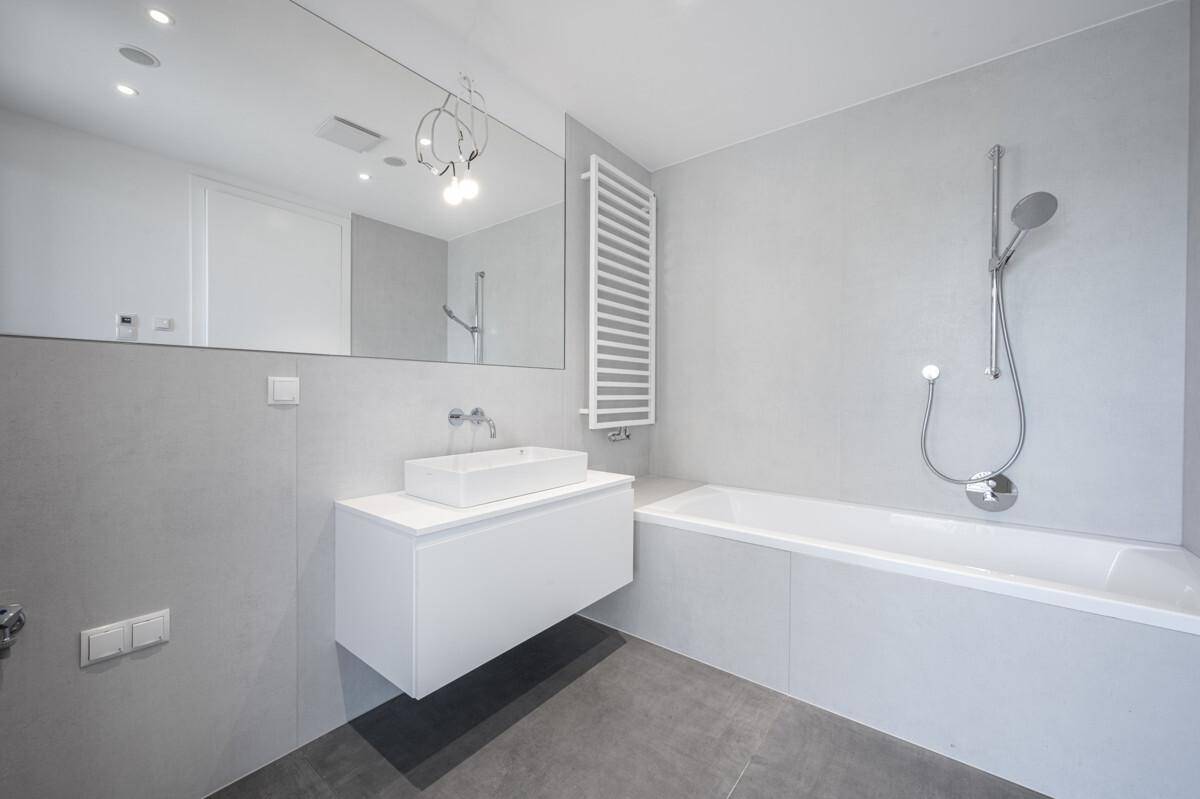 Helles Badezimmer mit Badewanne, integrierter Dusche und modernem Waschtisch.