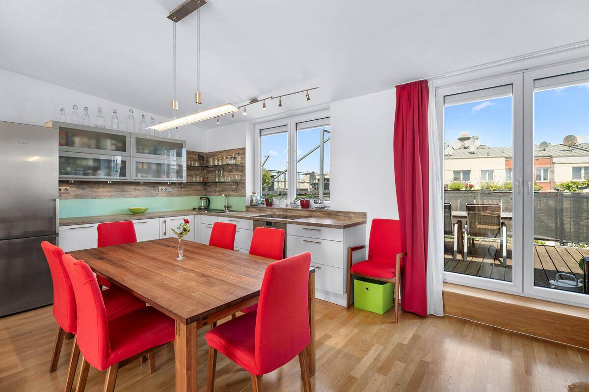 Moderne Küche mit Essbereich, roten Stühlen und direktem Zugang zur Dachterrasse.