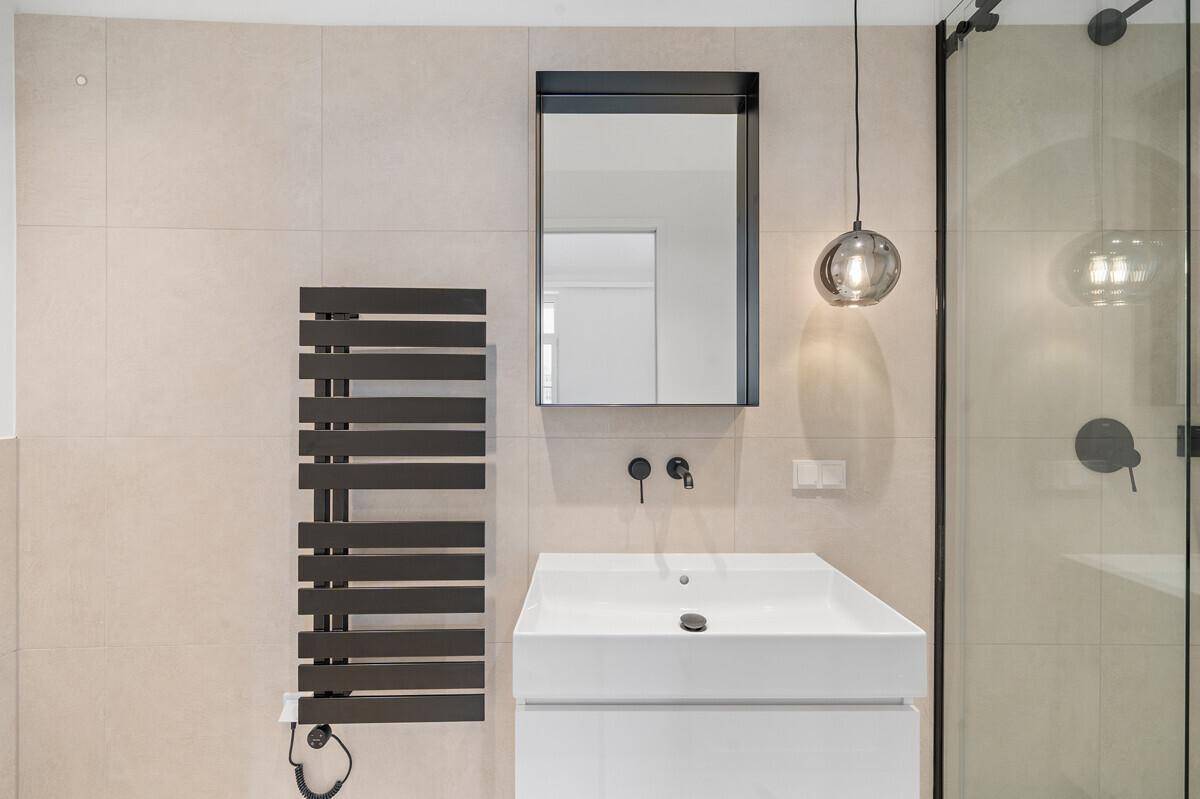 Elegantes Badezimmer mit modernem Waschtisch, beheiztem Handtuchhalter und großem Spiegel.
