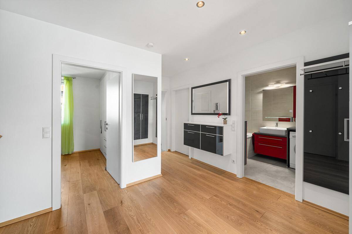 Flur mit Holzboden, großem Spiegel und Zugang zu Bad und Schlafzimmer.