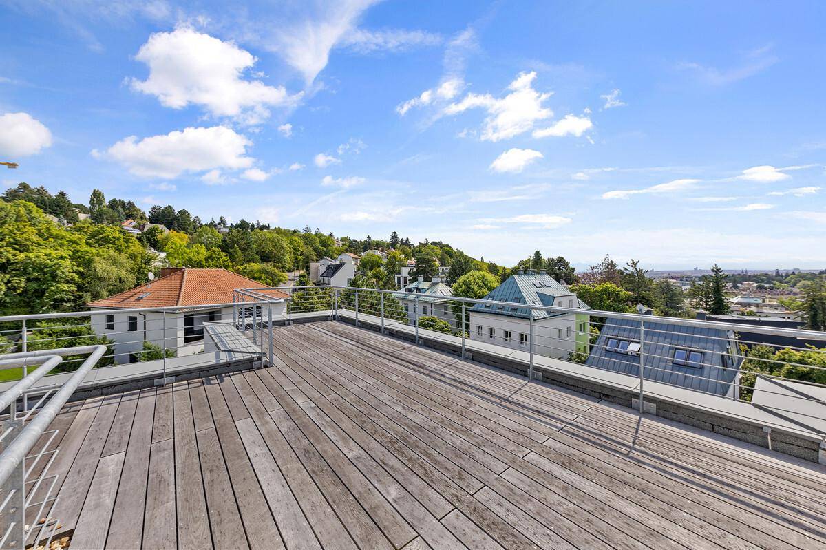 Große Dachterrasse mit Holzboden und weitem Blick über die grüne Umgebung.
