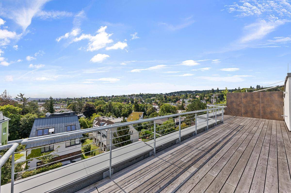Sonnige Dachterrasse mit Holzdielen und weitem Ausblick über die Stadt und Natur.