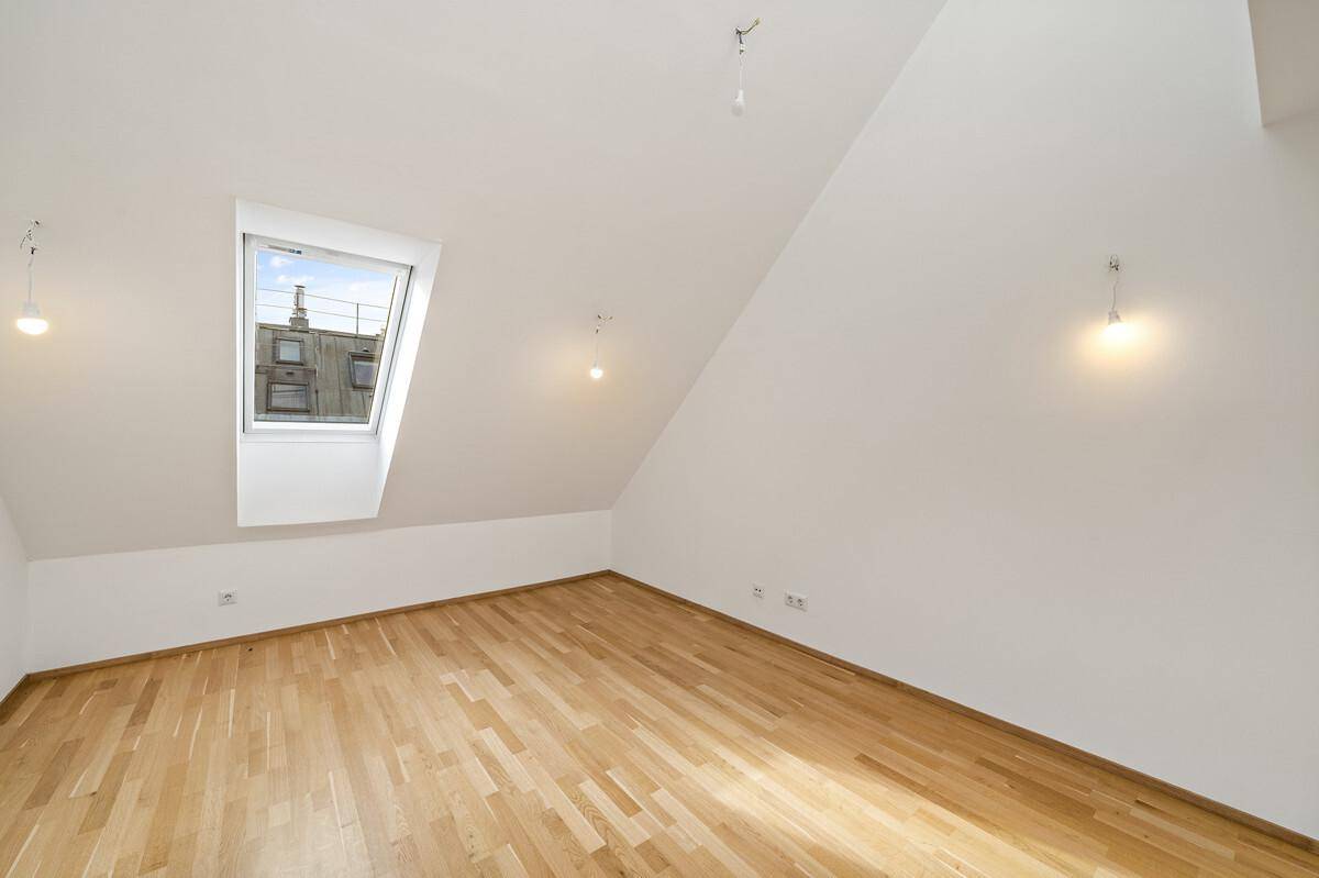 Lichtdurchflutetes Dachgeschosszimmer mit Parkettboden und einem großen Dachfenster.