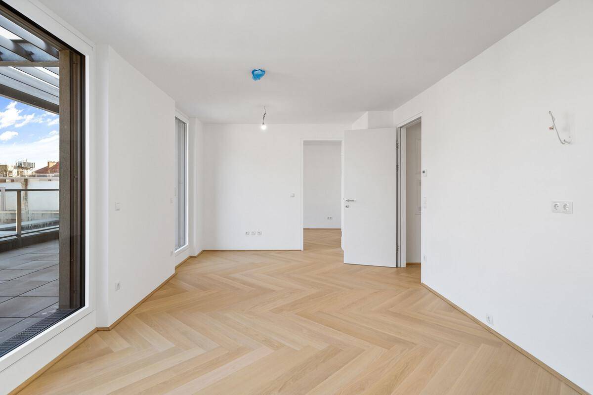 Geräumiger, heller Wohnbereich mit Parkettboden und Zugang zu weiteren Räumen der Wohnung.