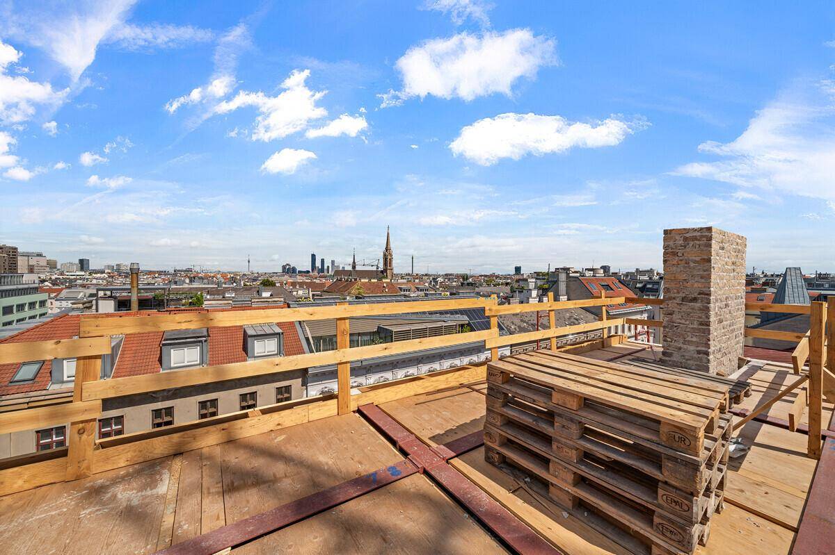 Baustelle auf dem Dach mit Holzpaletten und weitem Blick über die Dächer der Stadt.