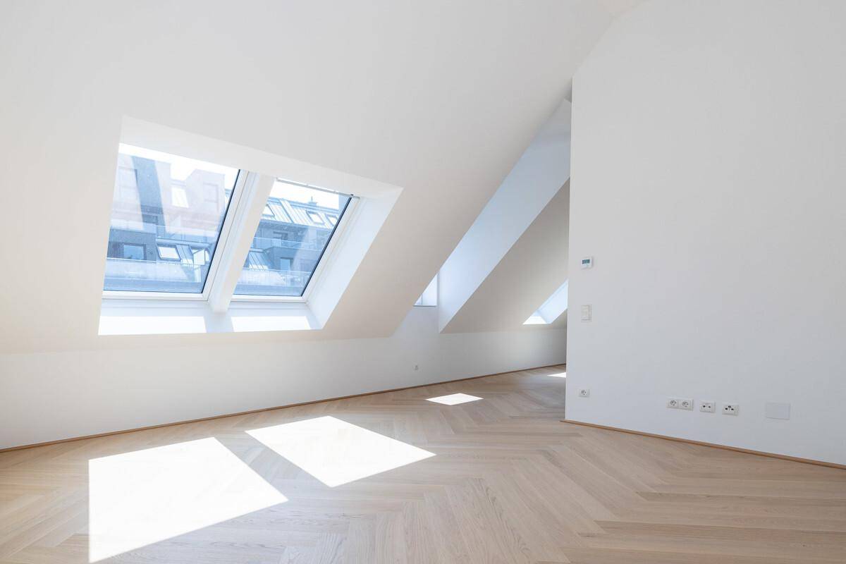 Lichtdurchfluteter Dachgeschossraum mit schrägen Decken und großen Dachfenstern, ideal für Wohnen oder Schlafen.