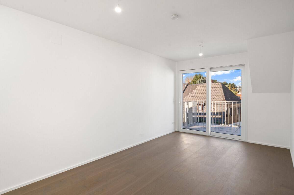 Geräumiger, heller Innenraum mit Holzboden und Schiebetür zum Balkon, bietet viel Tageslicht und Ausblick.