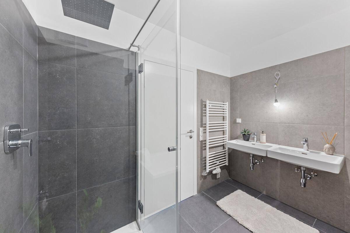 Modernes Badezimmer mit großer begehbarer Dusche, Doppelwaschbecken und Handtuchheizkörper.