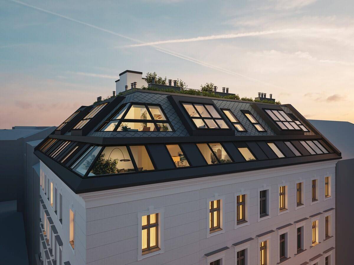 Dachgeschossansicht eines modernen Gebäudes mit großen Glasflächen und zahlreichen Dachfenstern bei Sonnenuntergang.