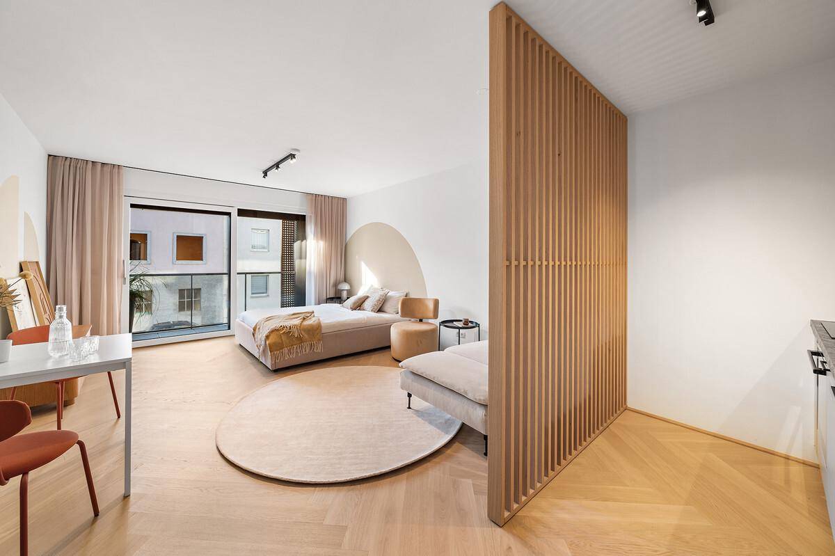 Modernes Schlafzimmer mit Holzboden, dekorativer Holzlamellenwand und viel Tageslicht.