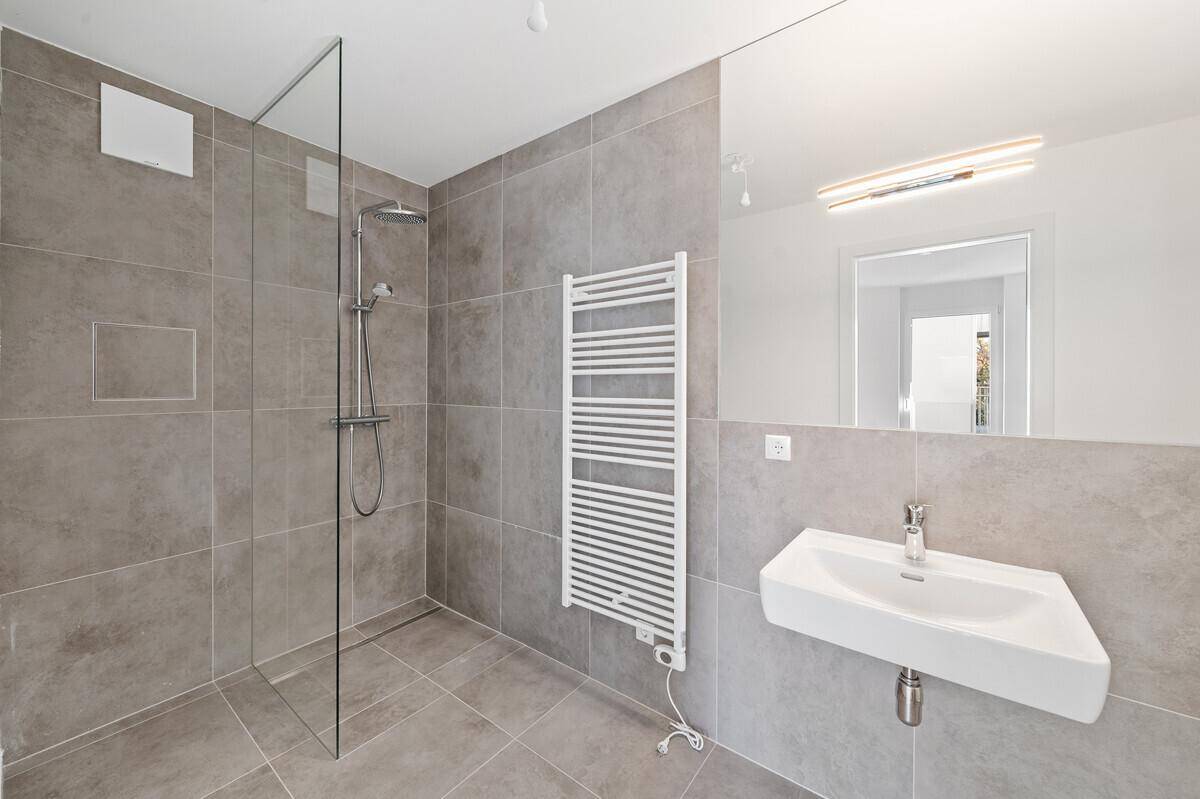 Modernes Badezimmer mit großer begehbarer Dusche, Einzelwaschbecken und Handtuchheizkörper.
