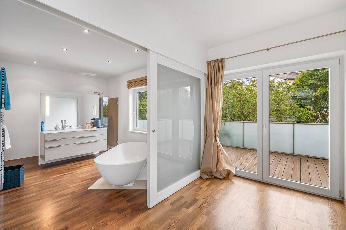 Modernes Badezimmer mit freistehender Badewanne, Doppelwaschbecken und Zugang zu einem Balkon.