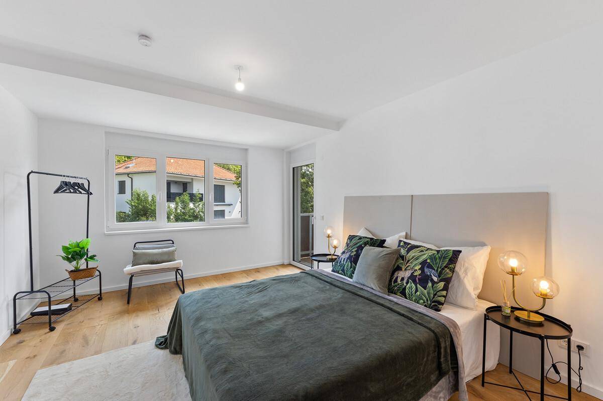 Modernes Schlafzimmer mit Holzboden, großem Fenster und Blick ins Grüne.