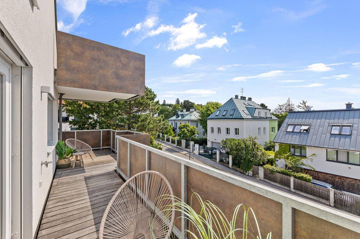 Langer Balkon mit Holzdielen und Panoramablick auf die Stadt und die grüne Landschaft.