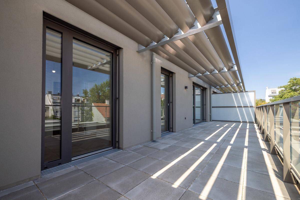 Helle Terrasse mit großen Schiebetüren und moderner Überdachung, ideal für Entspannung.