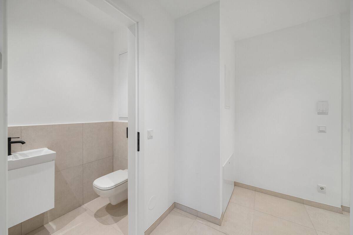 Modernes Gäste-WC mit wandhängender Toilette und kleinem Waschtisch in hellem Design.