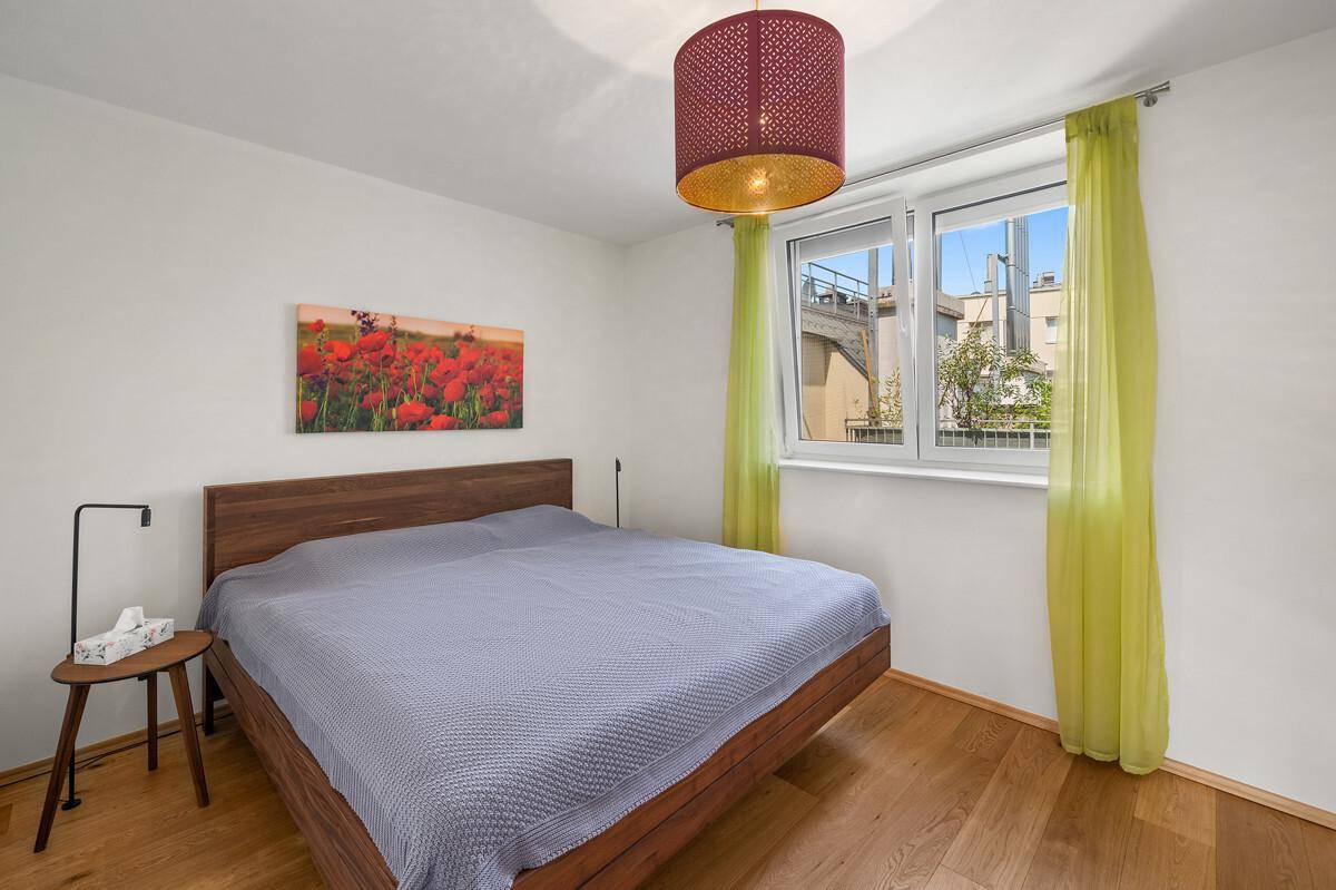 Helles Schlafzimmer mit Doppelbett, grünen Vorhängen und Blick ins Grüne.